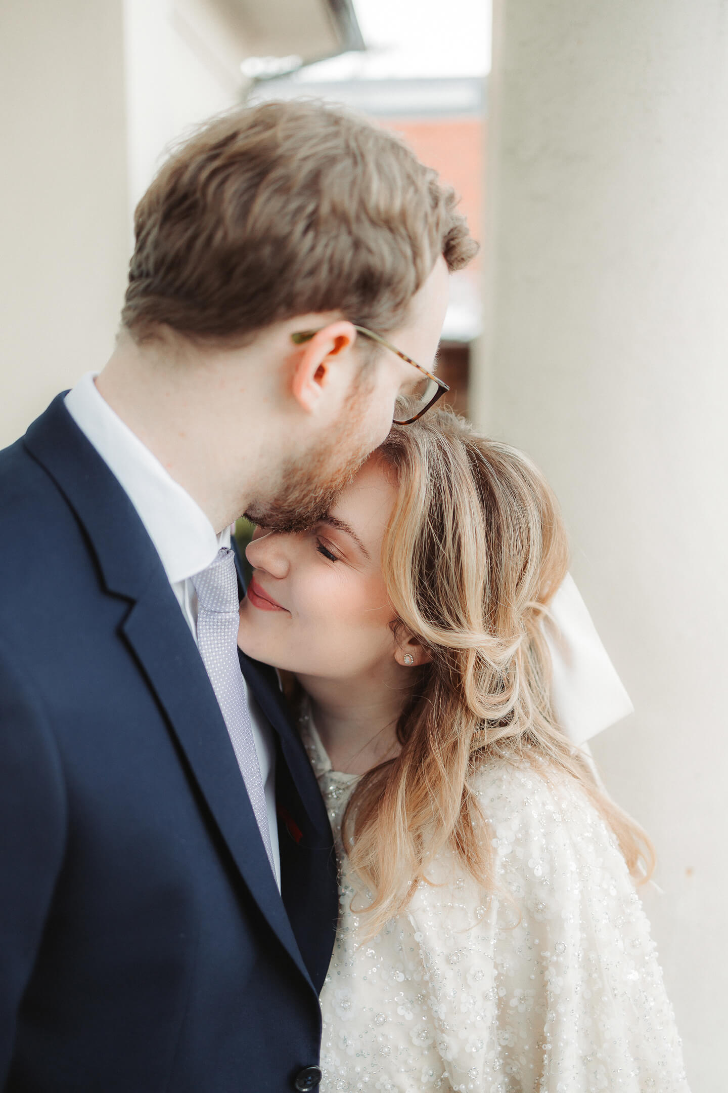 A newlywed couple shares an intimate moment as the husband gently kisses his wife.