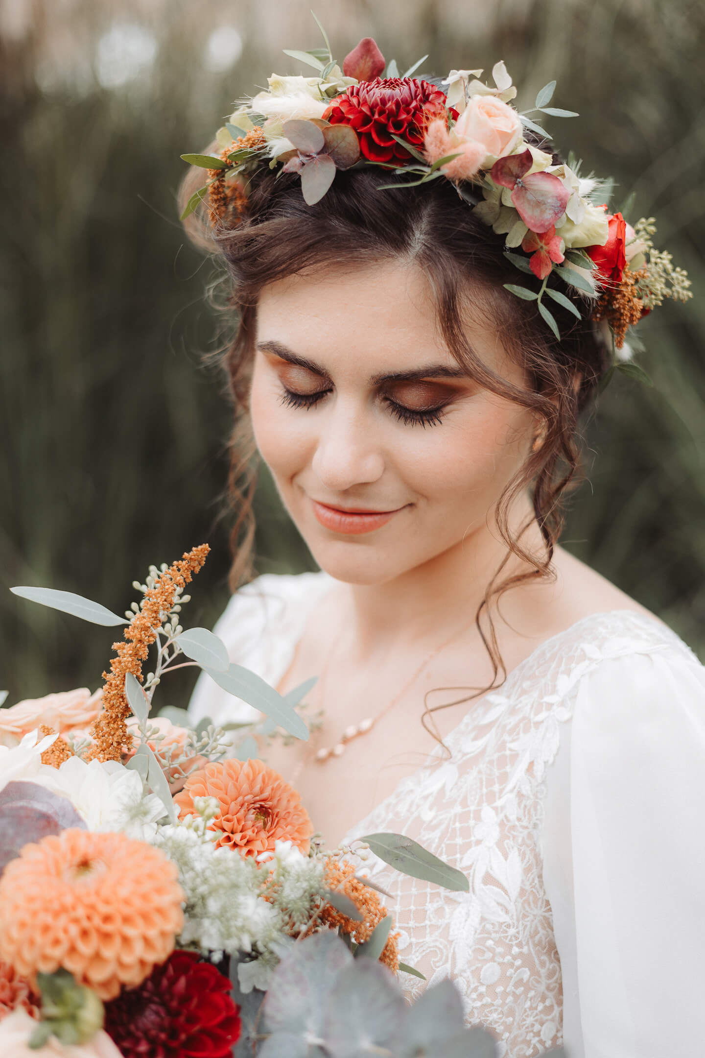 A smiling bride wearing a flower crown and holding a bouquet.