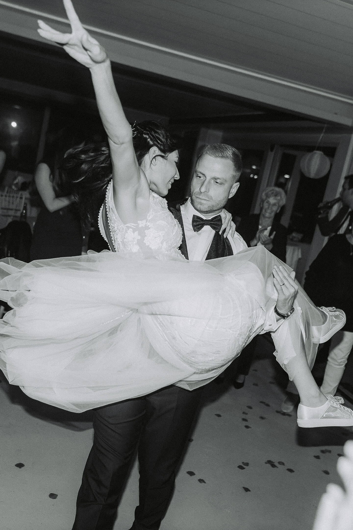 The groom lifts the bride into the air on the dance floor.
