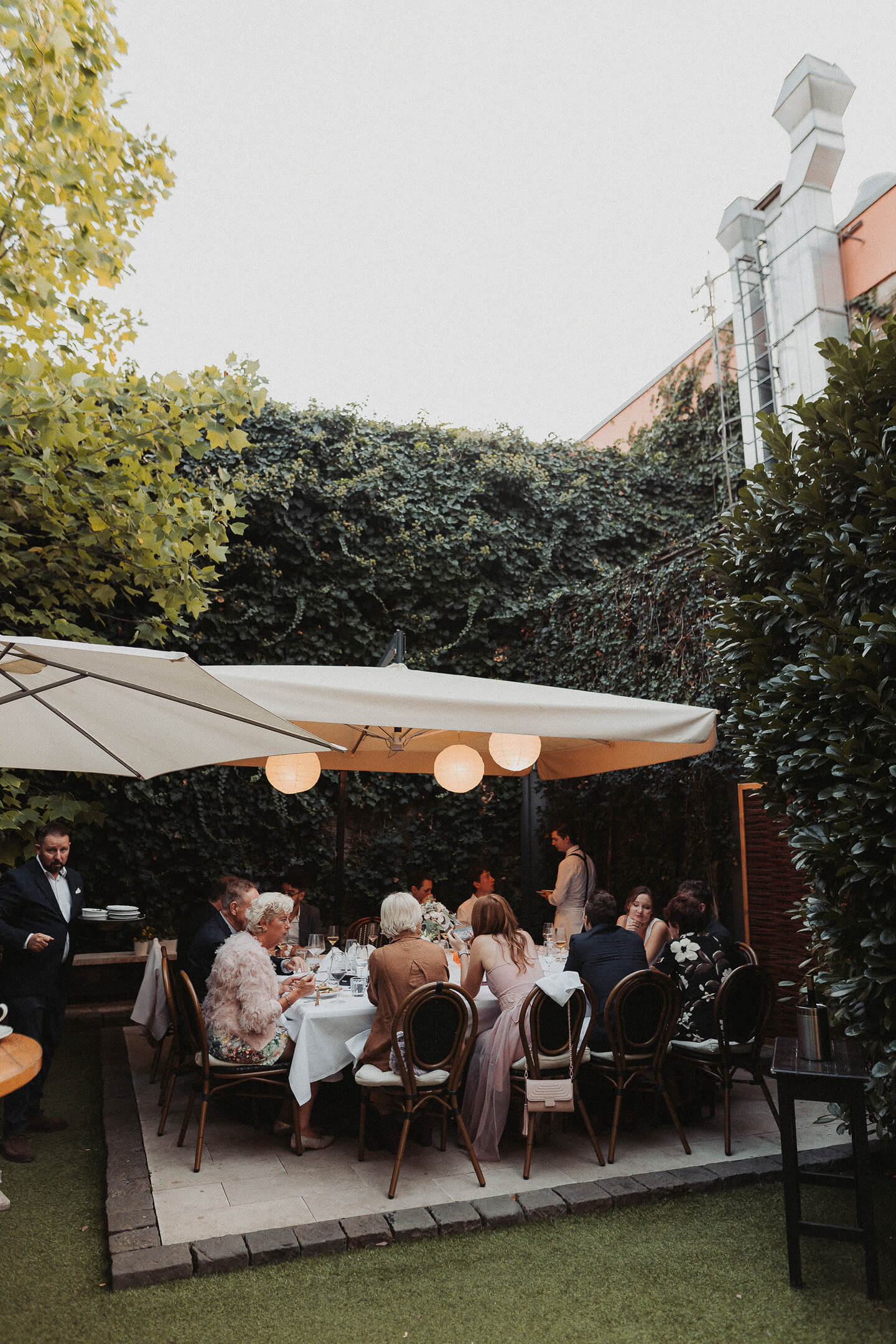 A wedding dinner in a charming garden, surrounded by elegant guests.
