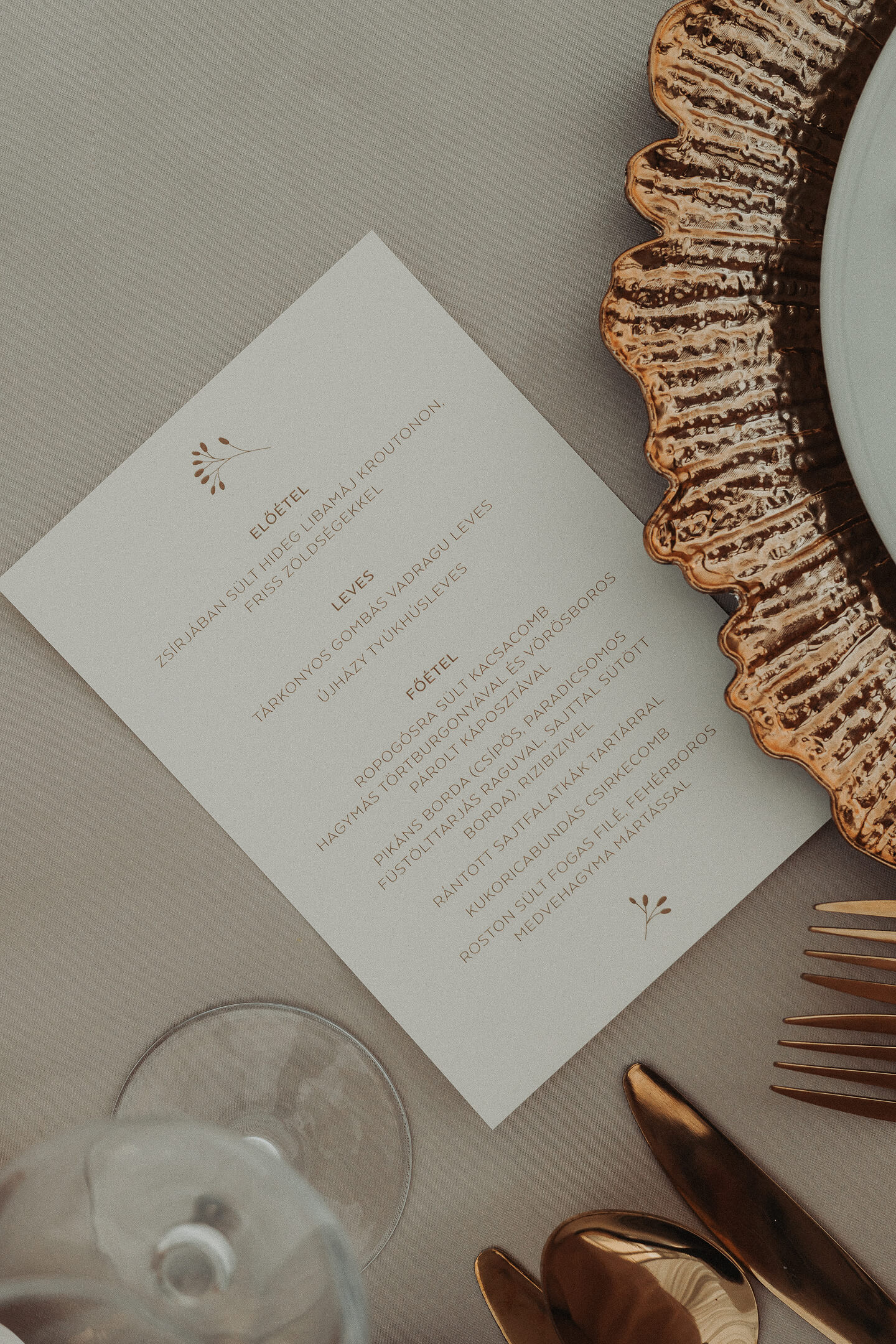 An elegant wedding menu card placed next to a gilded plate, with clean and tasteful typography.